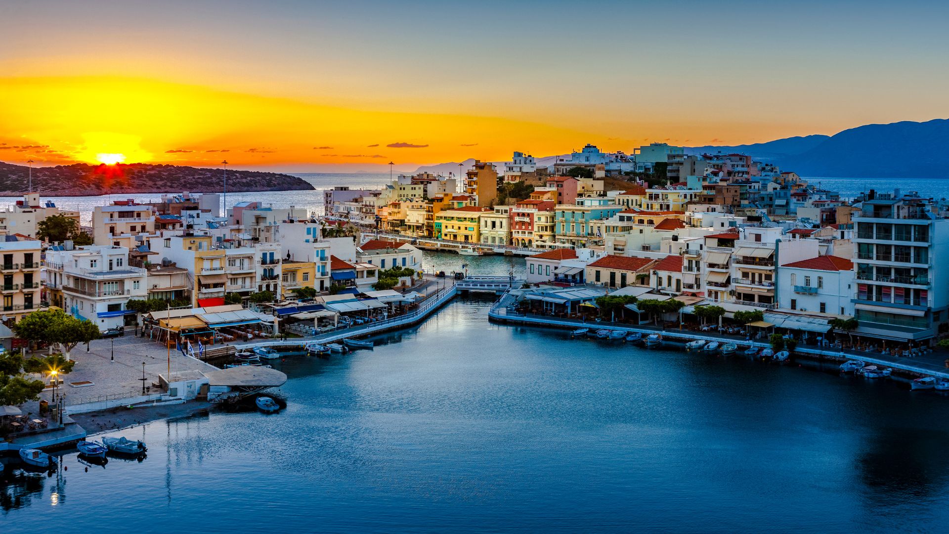 Sunset view of Lake Voulismeni surrounded by buildings in Agios Nikolaos, Crete.
