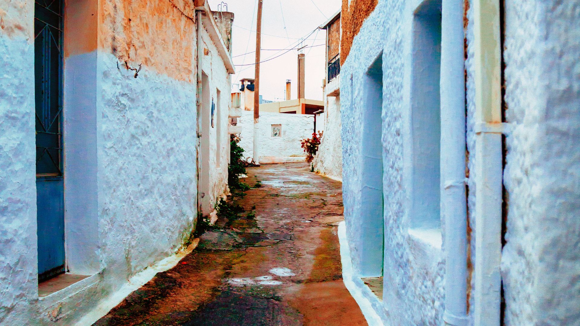 An outdoor seating area with blue wooden chairs and a small table, typical of a kafenio. 