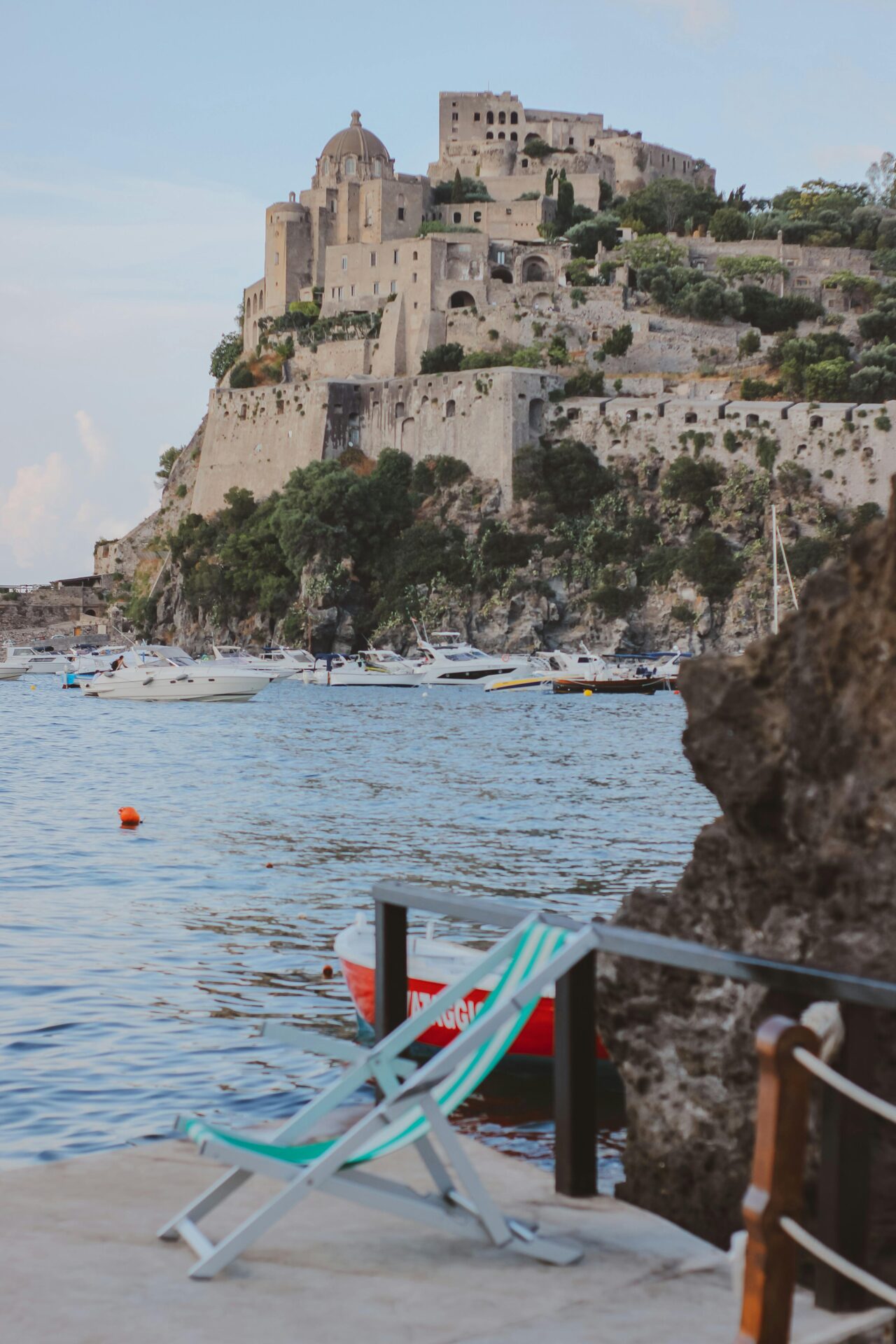 Historic Aragonese Castle with stone towers and fortified walls, perched on a hilltop overlooking the sea in southern Italy.