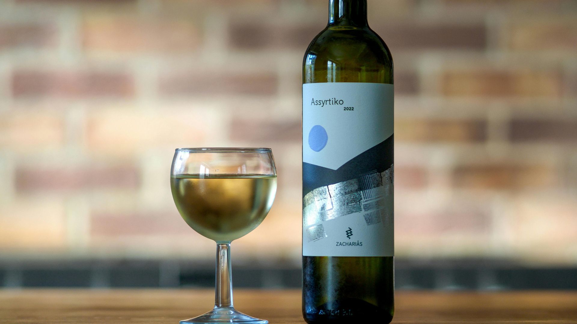 A bottle and a glass of Assyrtiko wine.