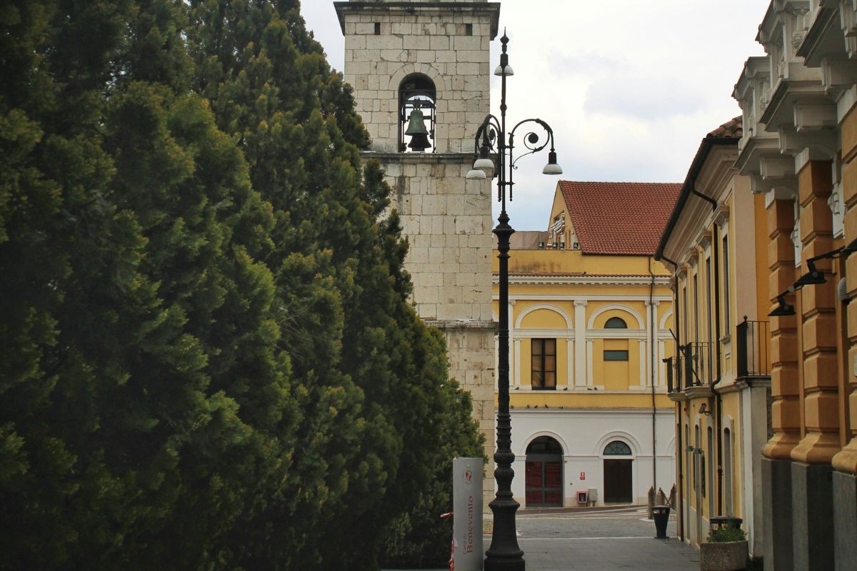 Bell tower and colorful historic buildings along a quiet street in Benevento, Italy.