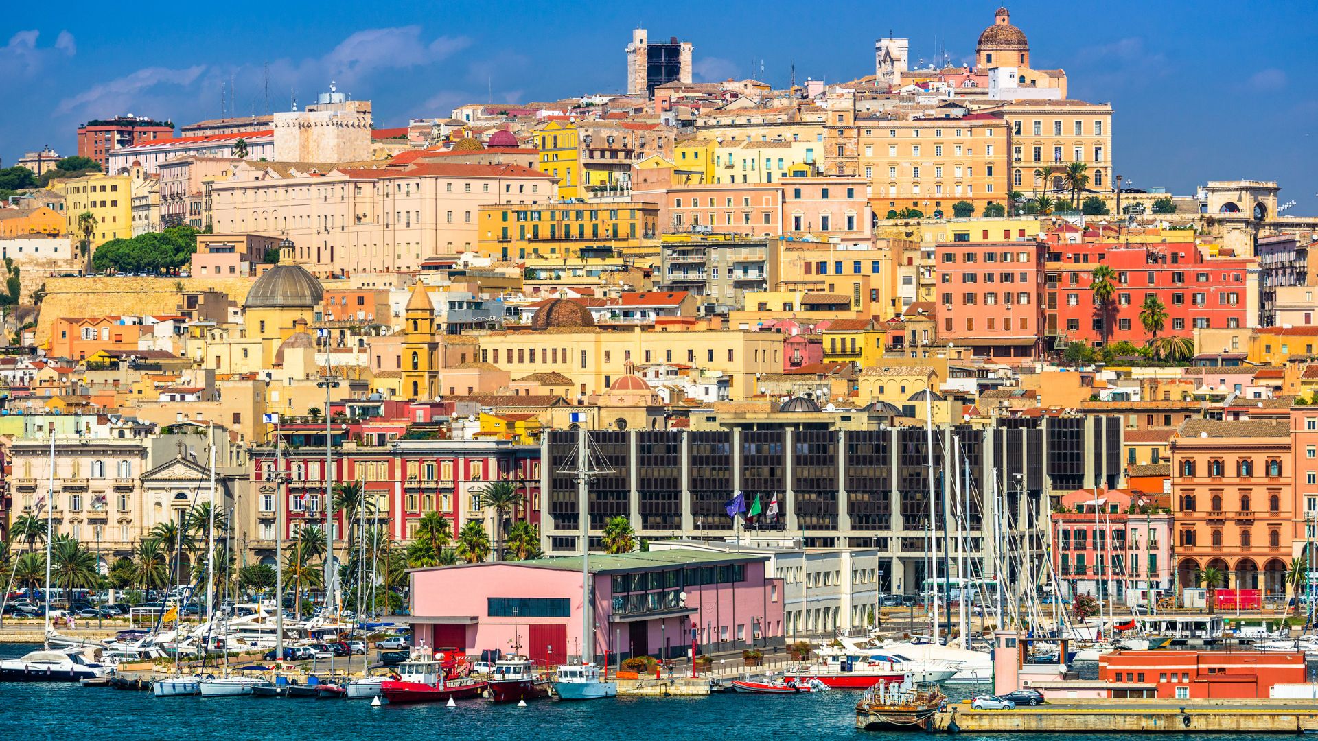 Colorful building, boats, and deep blue see of Cagliari, Sardinia, Italy.