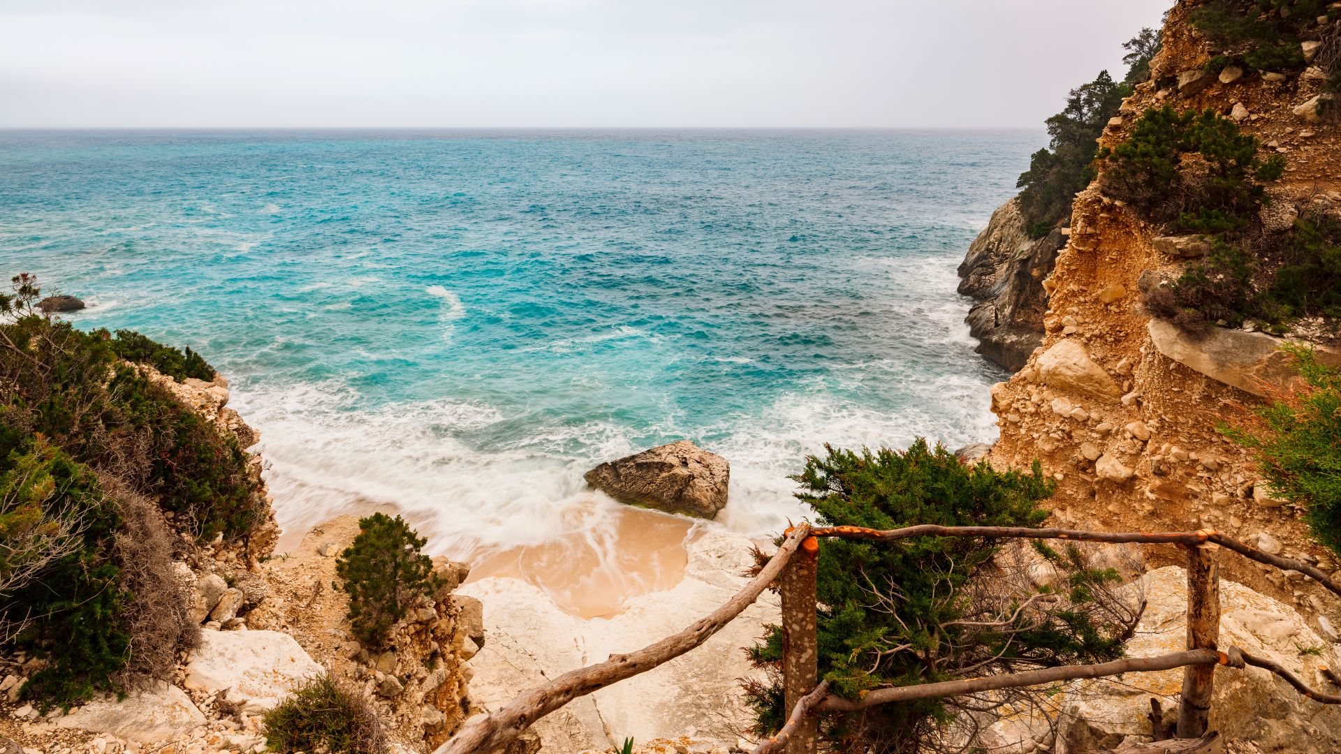 Scenic view of turquoise waters, rocky shores, and white sand beach of Cala Goloritzé in Sardinia, Italy