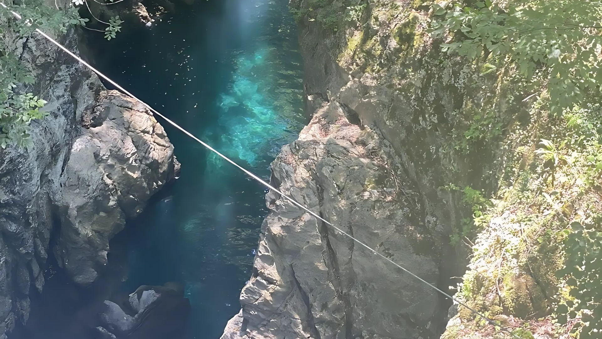 Image shows a zipline above river in Canyon Adventure Park .