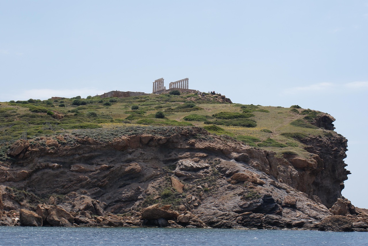 Distant view of the Temple of Poseidon atop a rocky hill.