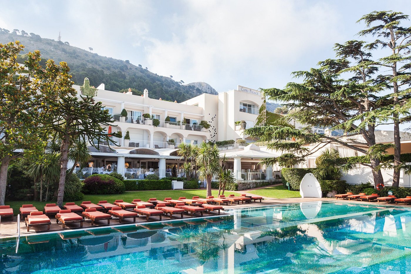 Elegant view of Capri Palace hotel with poolside loungers and lush greenery in Capri, Italy.