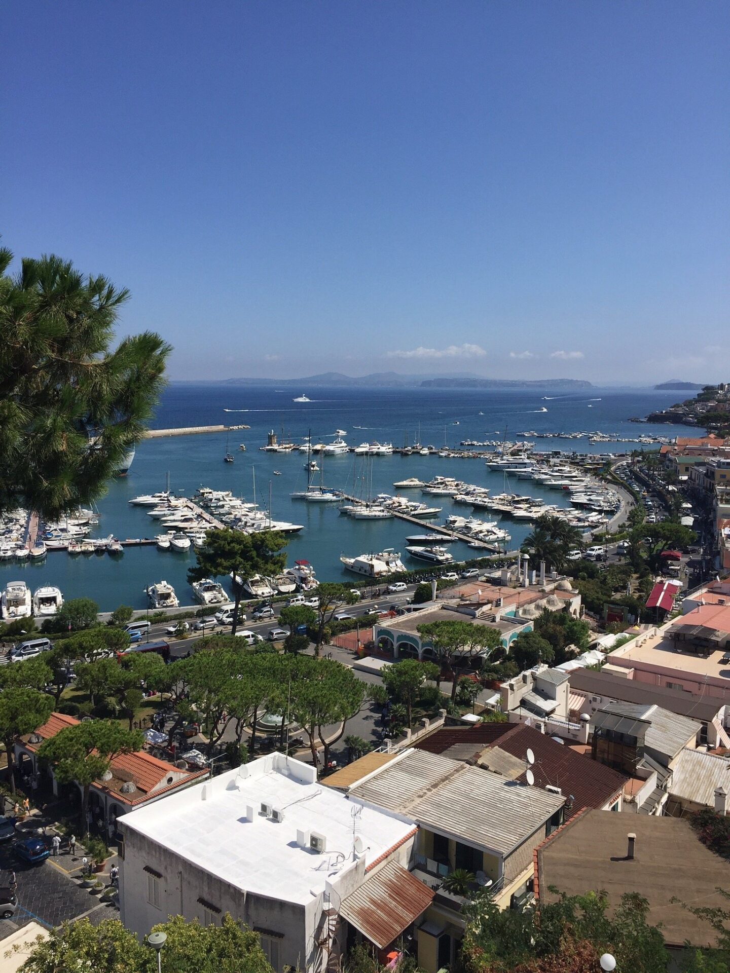 Scenic view of Casamicciola, a seaside town in Ischia, Italy, featuring a marina filled with boats and yachts, with the coastline and distant islands in the background.