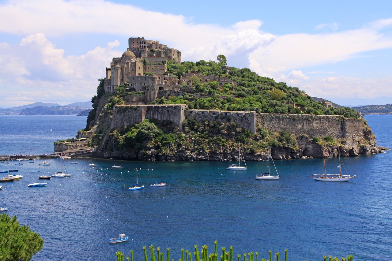 Aragonese Castle (Castello Aragonese) on a rocky islet surrounded by the sea in Ischia, Italy, with boats floating nearby.