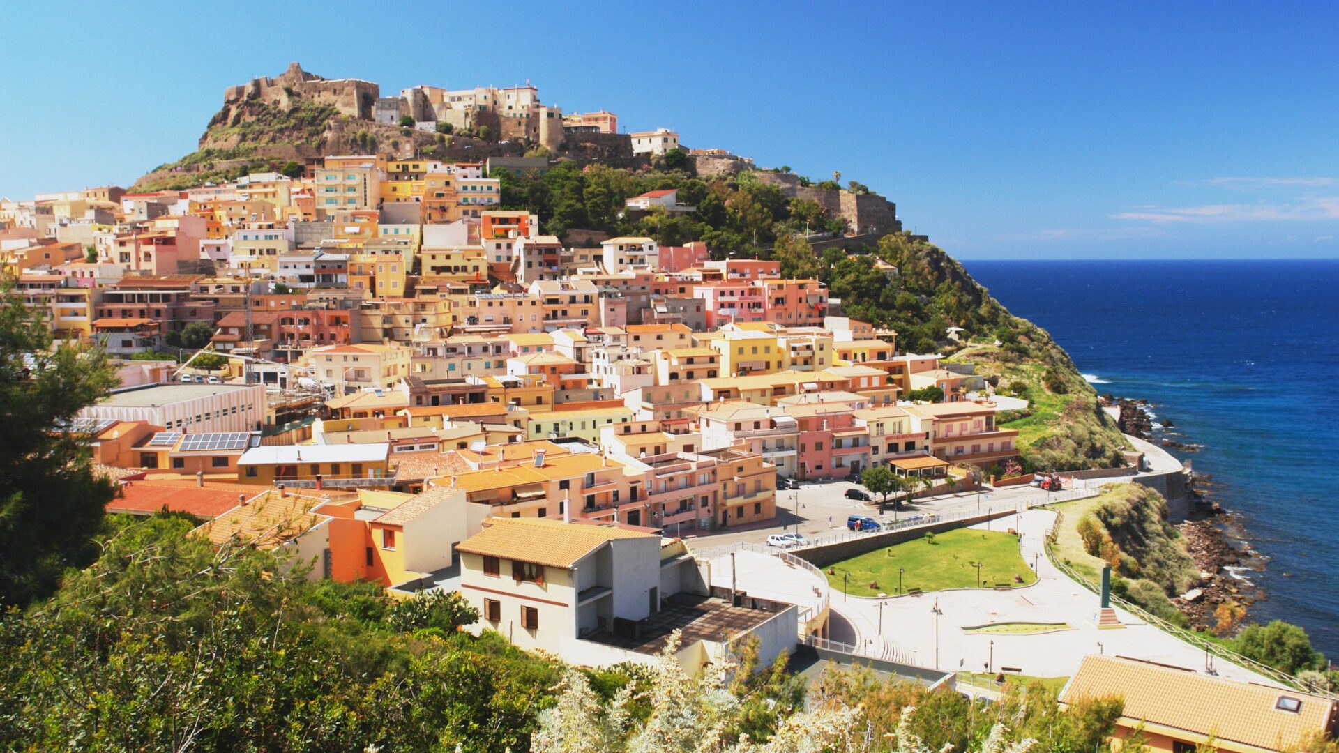 A panoramic view of the town of Castelsardo, Sardinia, featuring its hilltop castle and colorful houses overlooking the sea.
