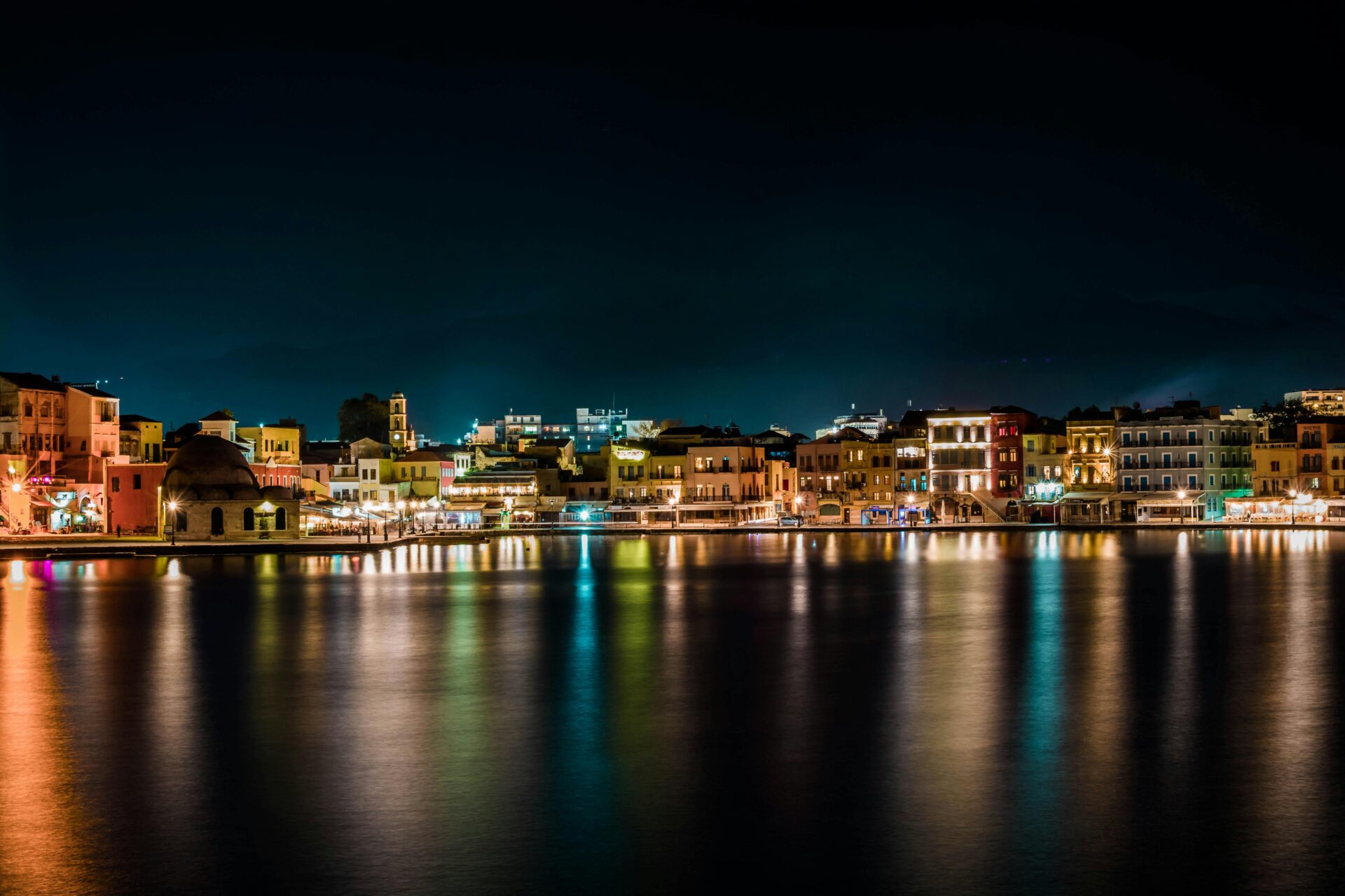 Chania harbor and village illuminated at night with glowing reflections on the water