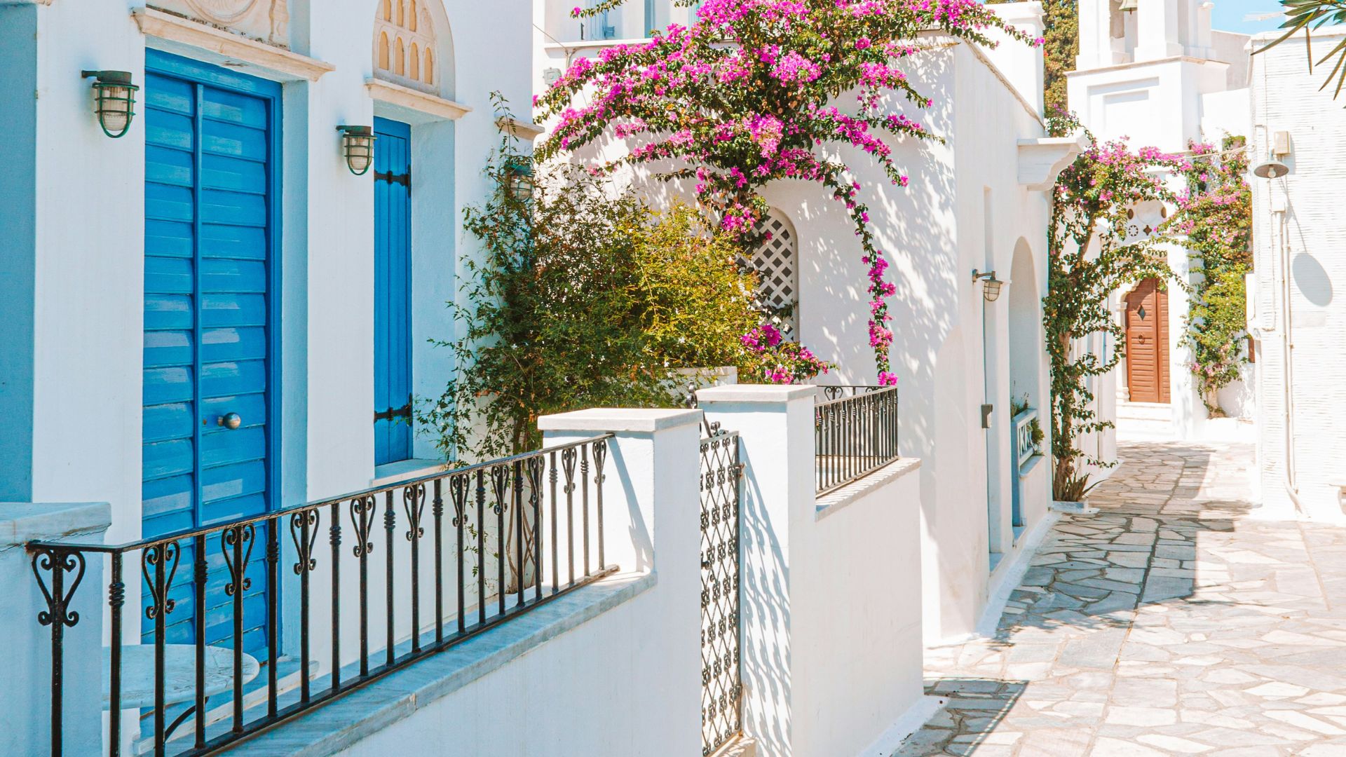 Whitewashed buildings with blue doors and bougainvillea in Mykonos, Greece