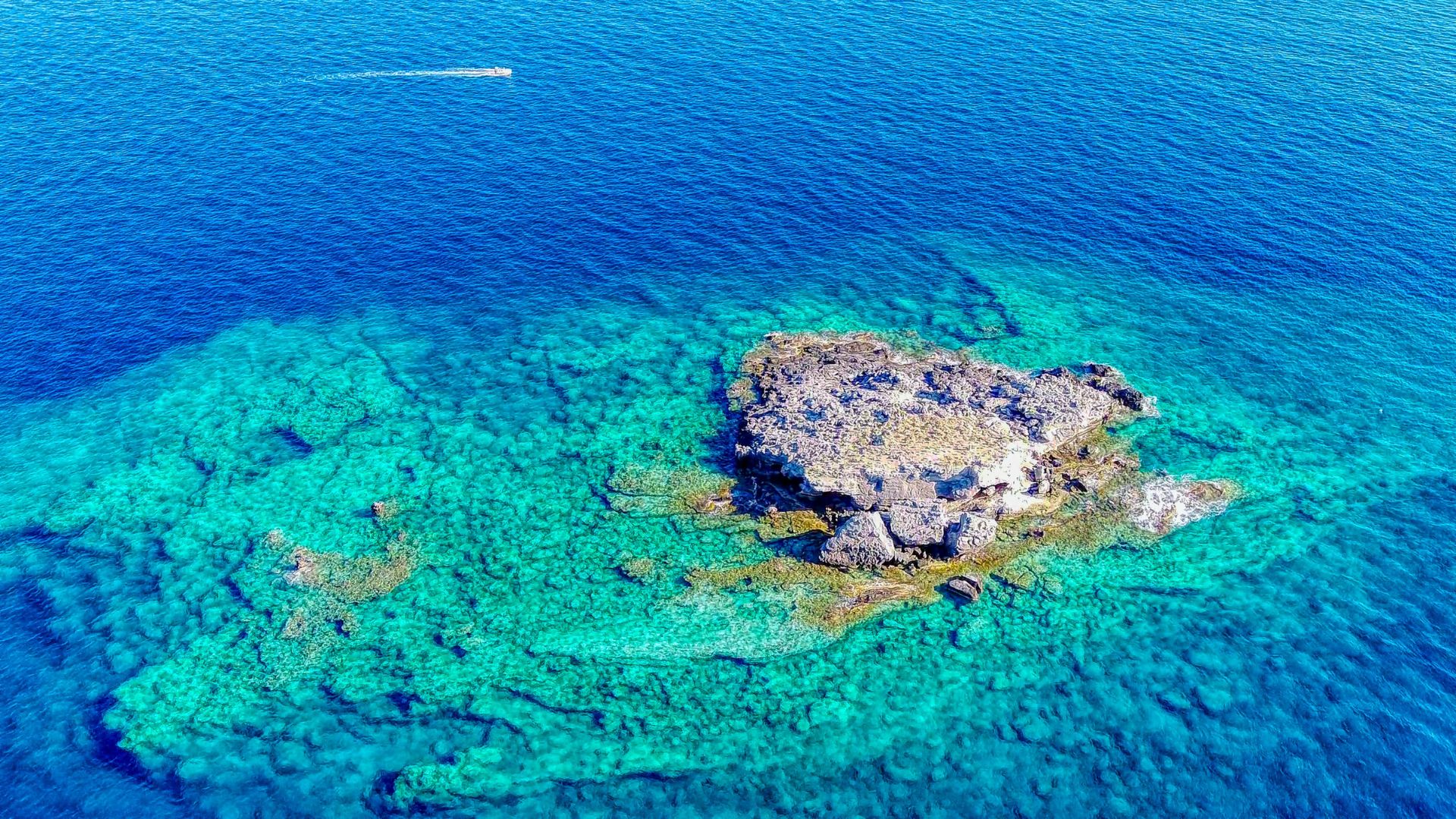 Aerial view of a small island with clear turquoise waters.