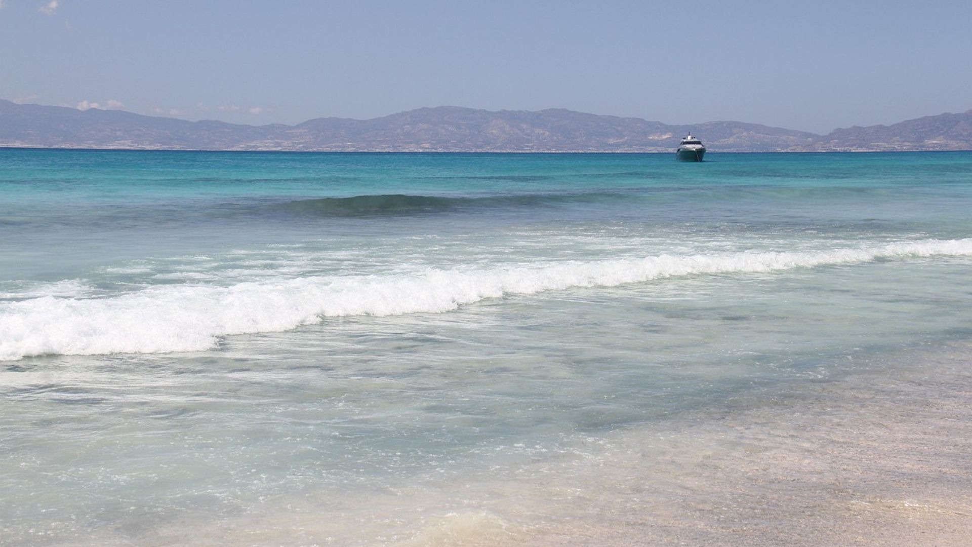 Turquoise waters and golden sands of Chrissi Island, with mountains in the distance.