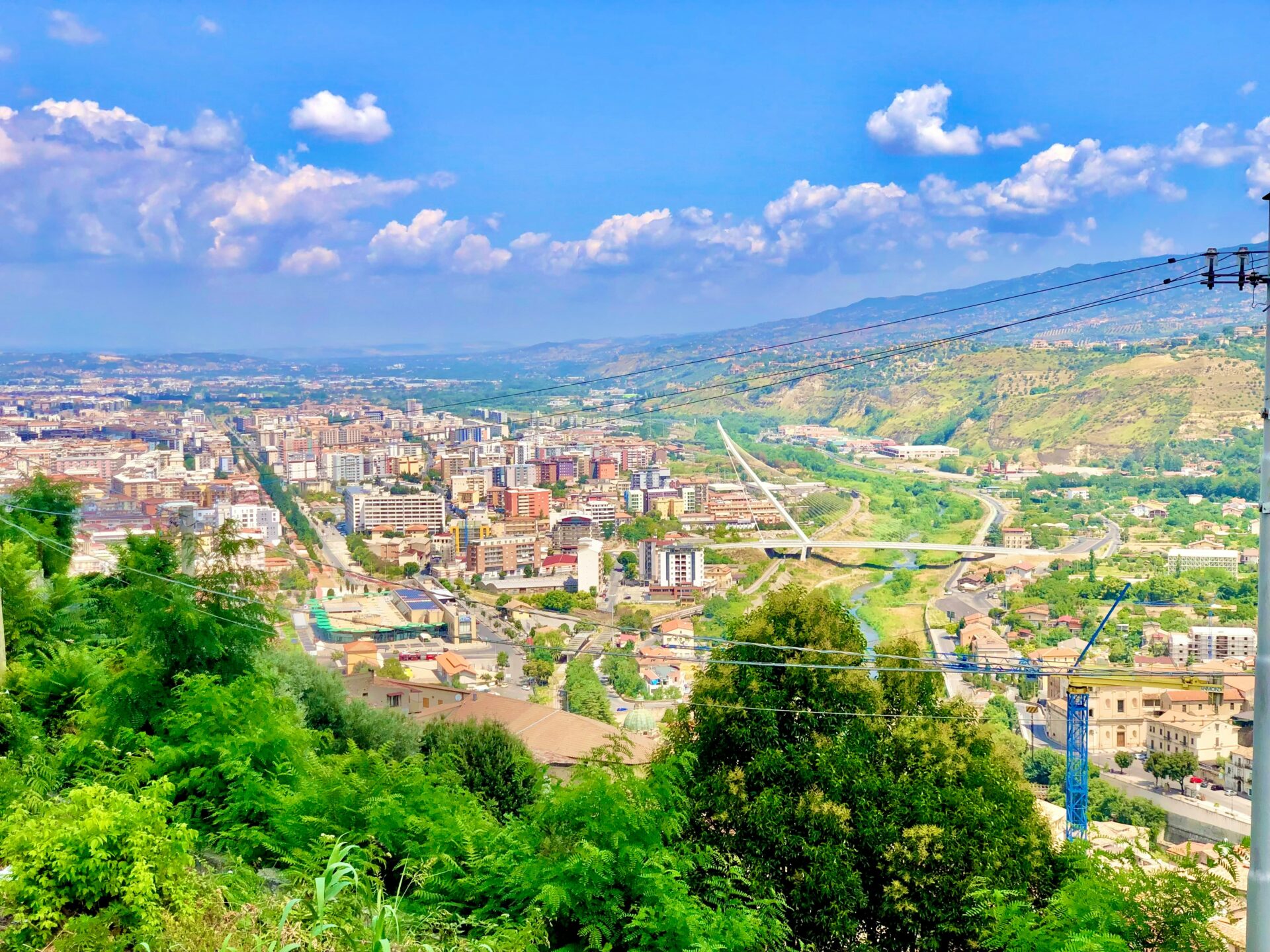 Panoramic view of Cosenza, showcasing its charming townscape with historic buildings nestled between rolling hills.