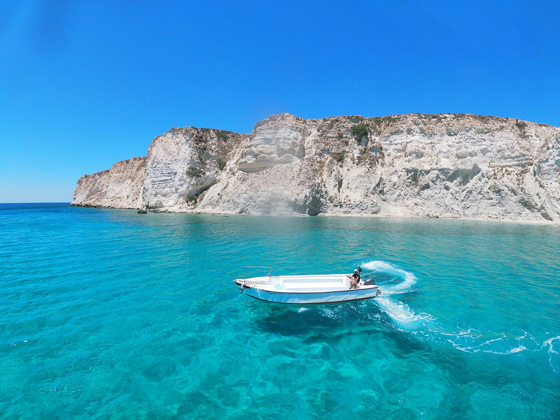 Clear blue waters meeting a cliff-lined shore in Crete.