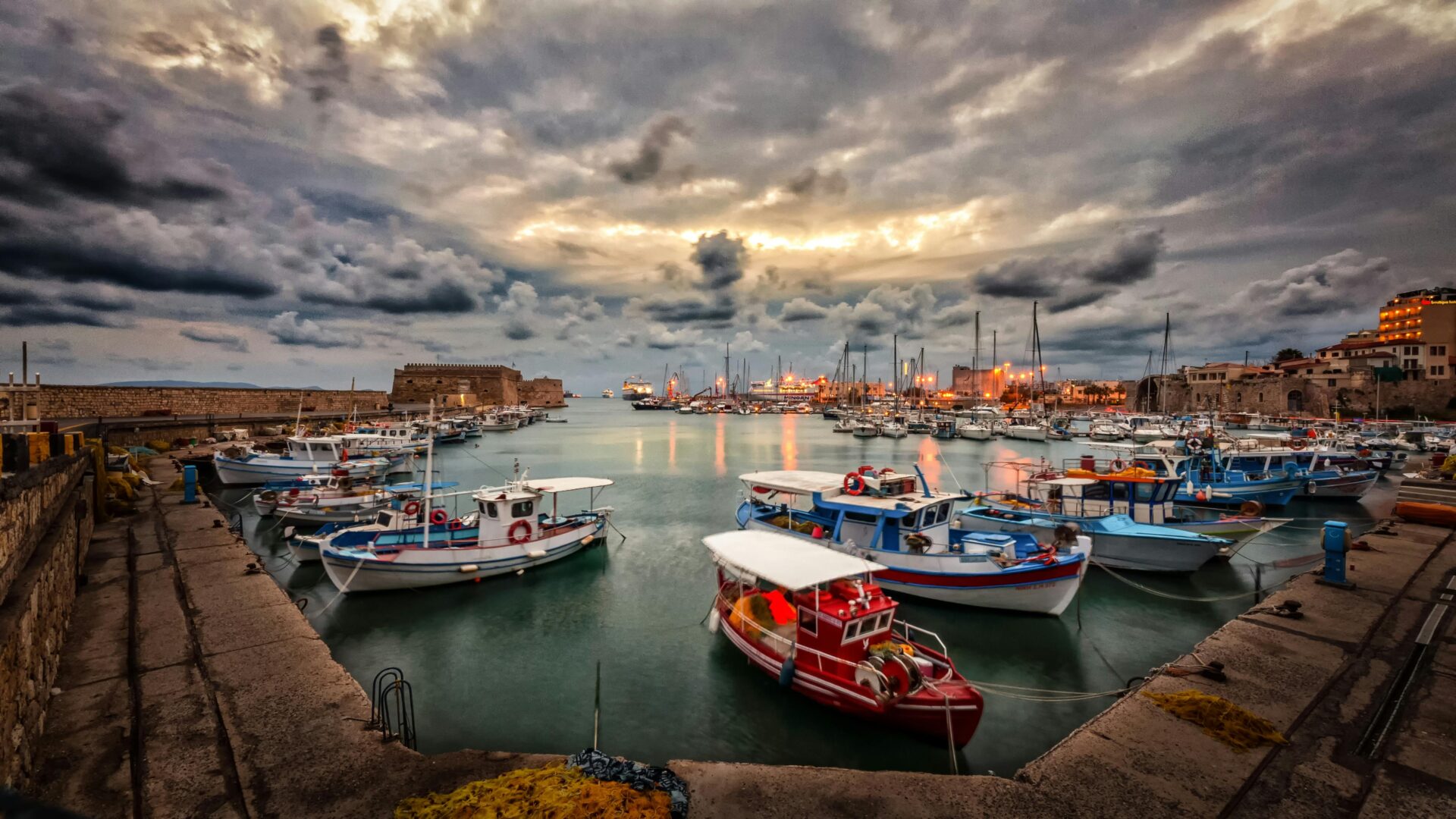 Fishing boats gently floating at dusk near a Cretan village