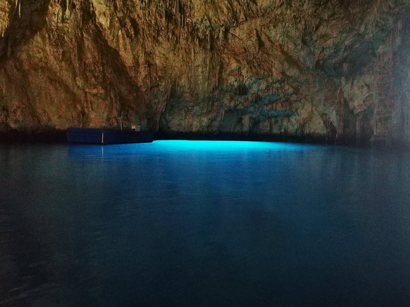 Inside view of the Emerald Grotto (Grotta dello Smeraldo) with glowing blue-green water and rocky cave walls on the Amalfi Coast, Italy.