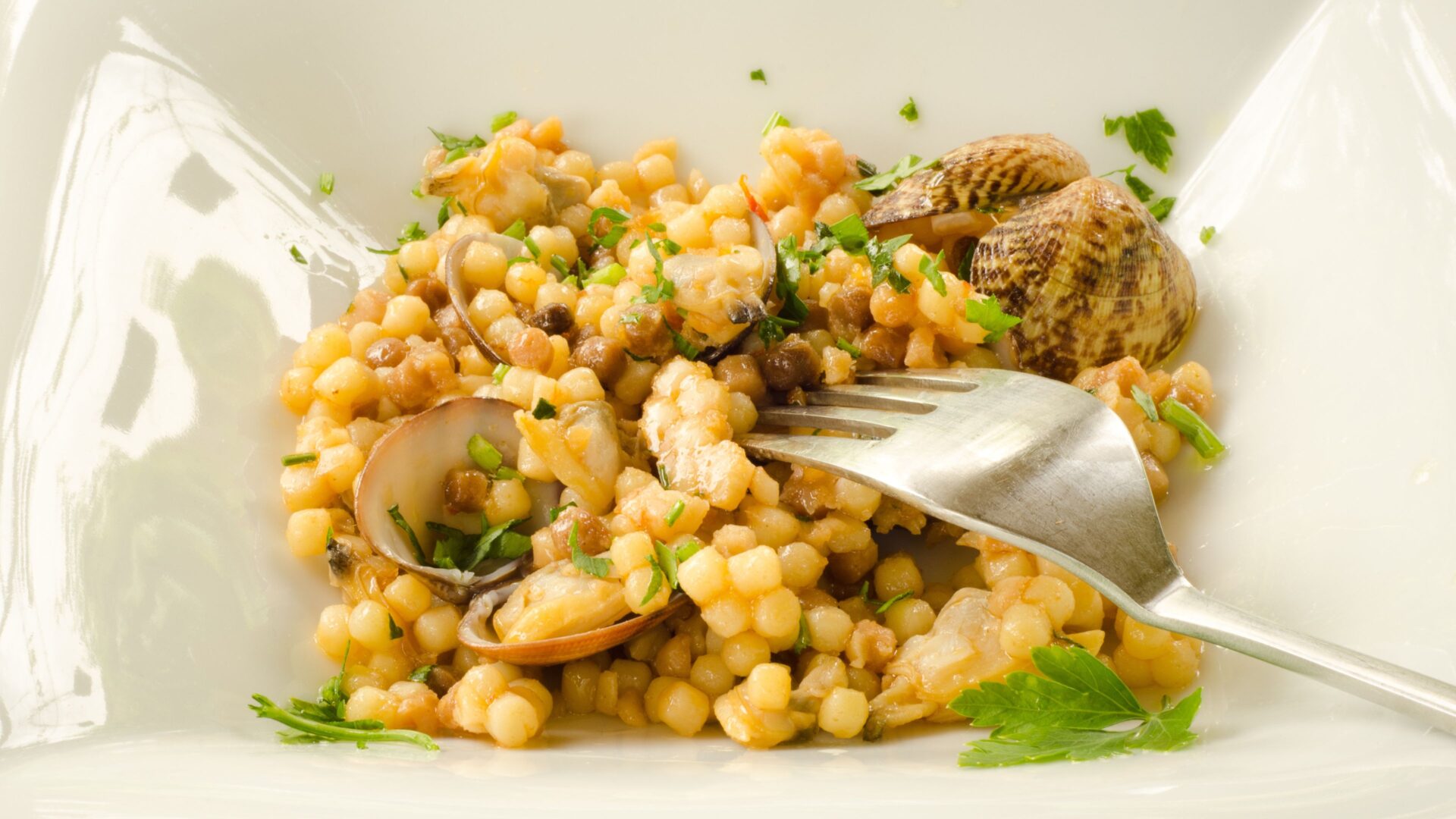 Fregola con arselle on a plate. 