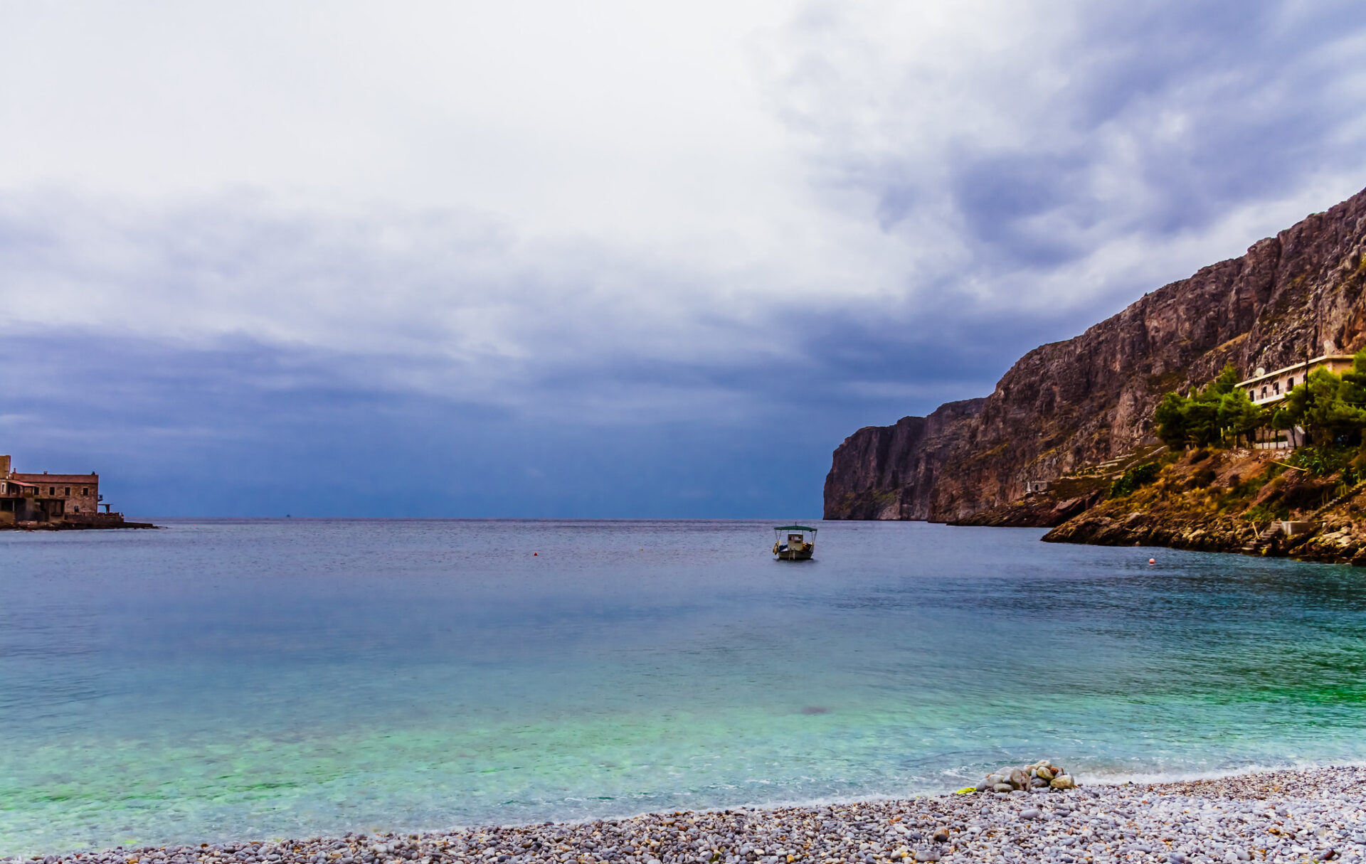 The dramatic cliffs of Gerolimenas, with their weathered surfaces contrasting against the calm, turquoise sea below.