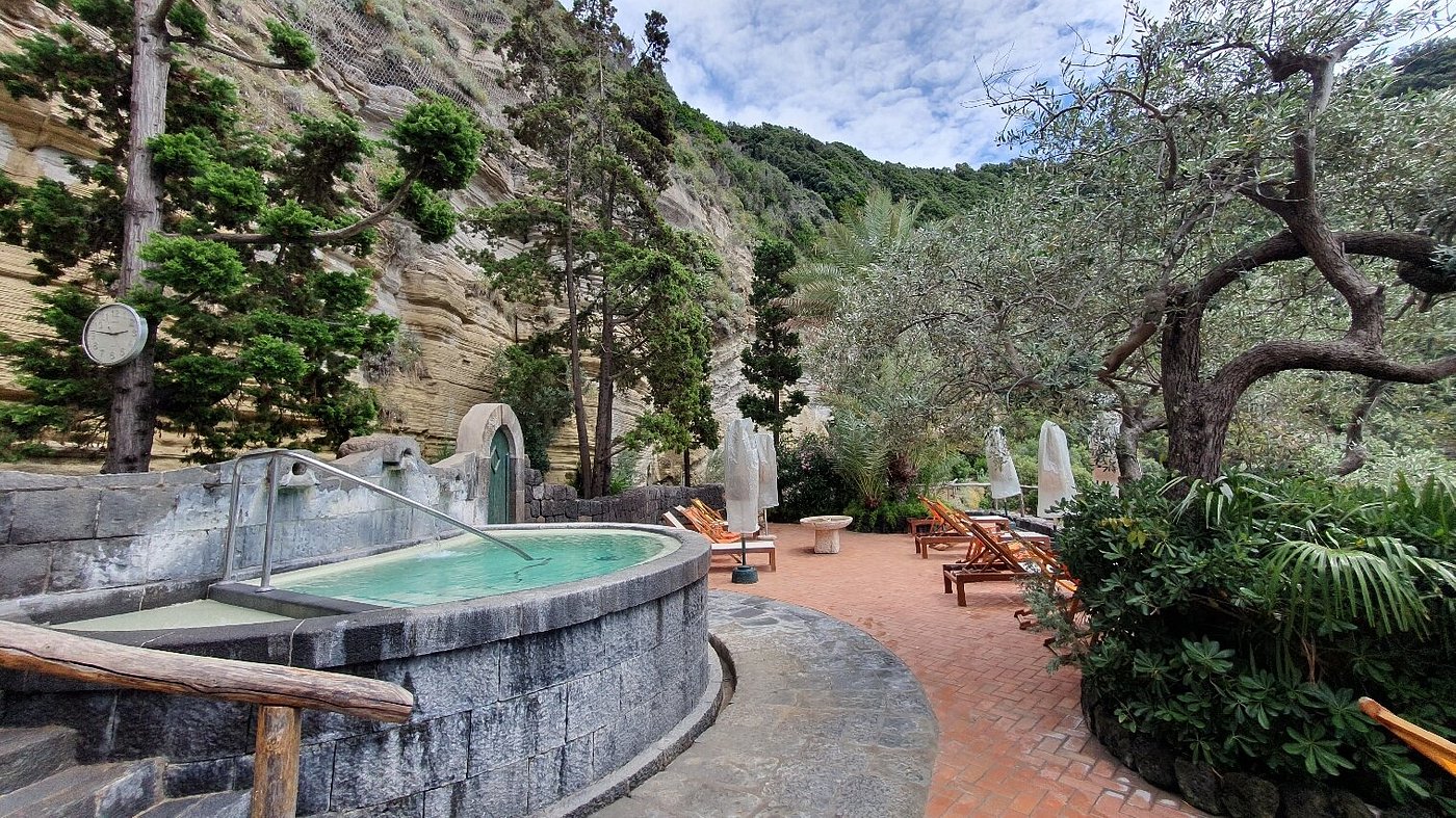 Outdoor thermal pool surrounded by lush greenery at Giardini Poseidon Terme in Ischia, Italy.