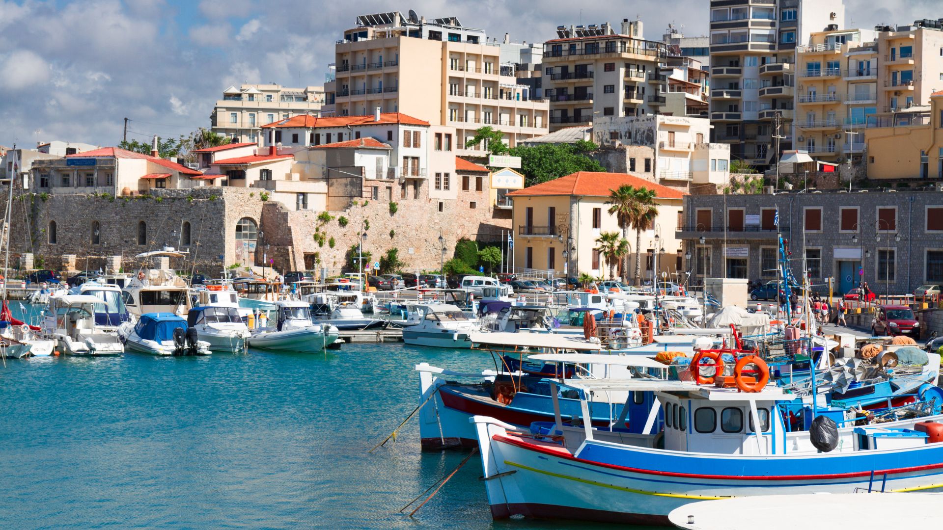 Boats in the harbor of Heraklion, Crete, with the city skyline in the background.