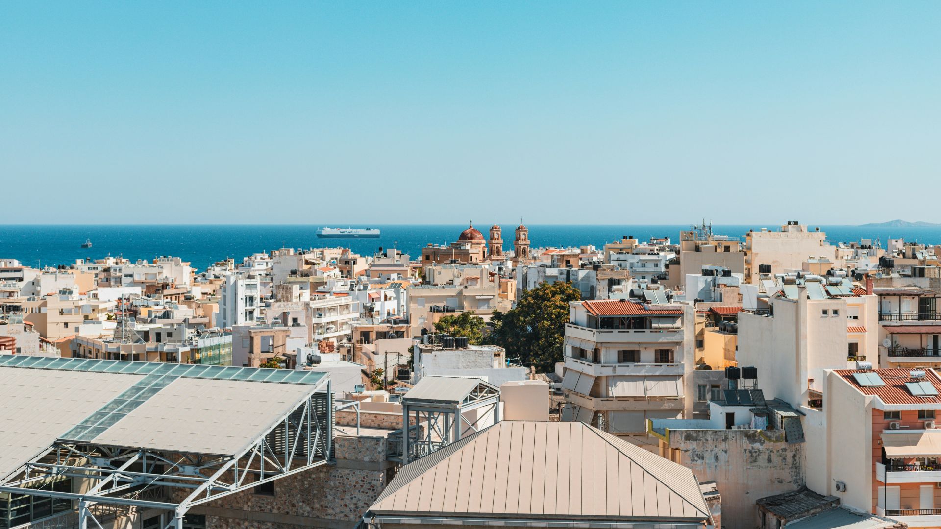 Aerial view of Heraklion, Crete, featuring the city's architecture, the sea, and clear sky.