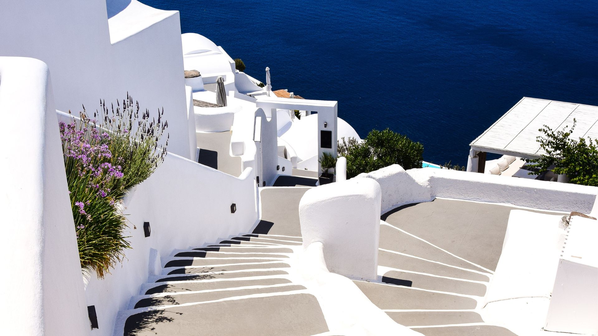Winding staircase in Imerovigli, Santorini, with white buildings and a sea view.