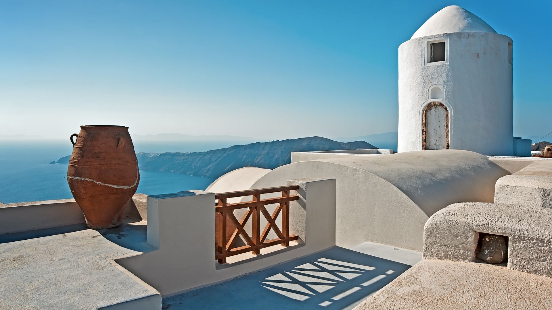 White buildings and a terracotta pot overlooking the sea in Santorini.