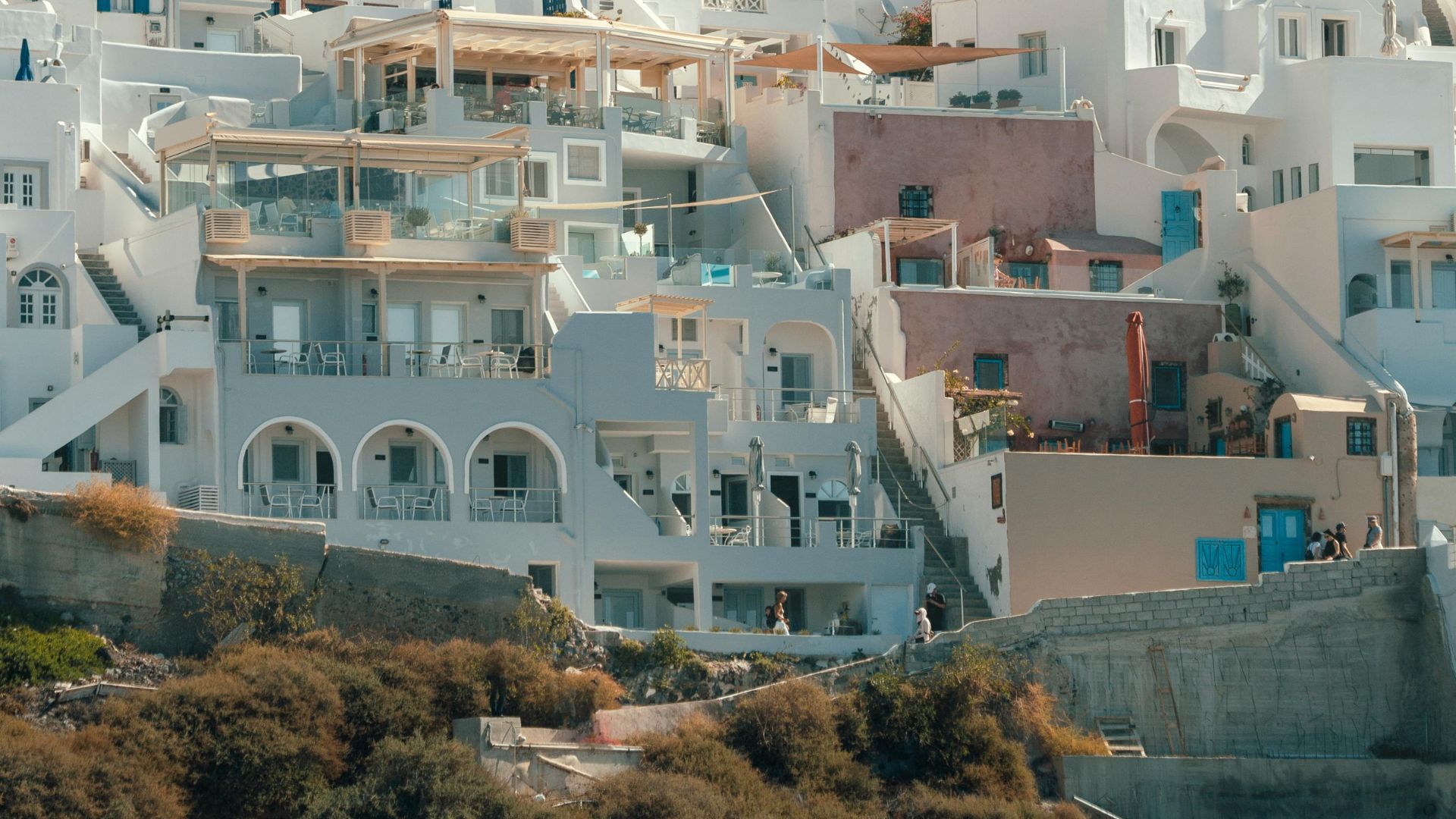 Whitewashed buildings cascade down a hillside in Imerovigli, Santorini, overlooking the Aegean Sea.
