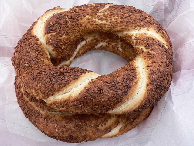 A round Greek sesame bread ring known as koulouri, placed on parchment paper.