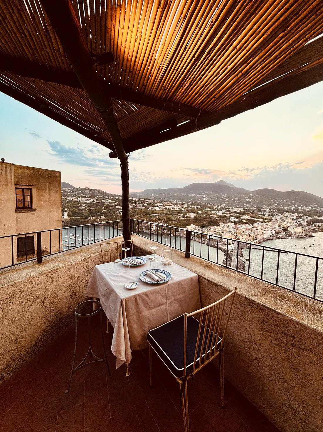 Romantic terrace dining setup at La Cucina Del Monastero overlooking the sea and town at sunset.