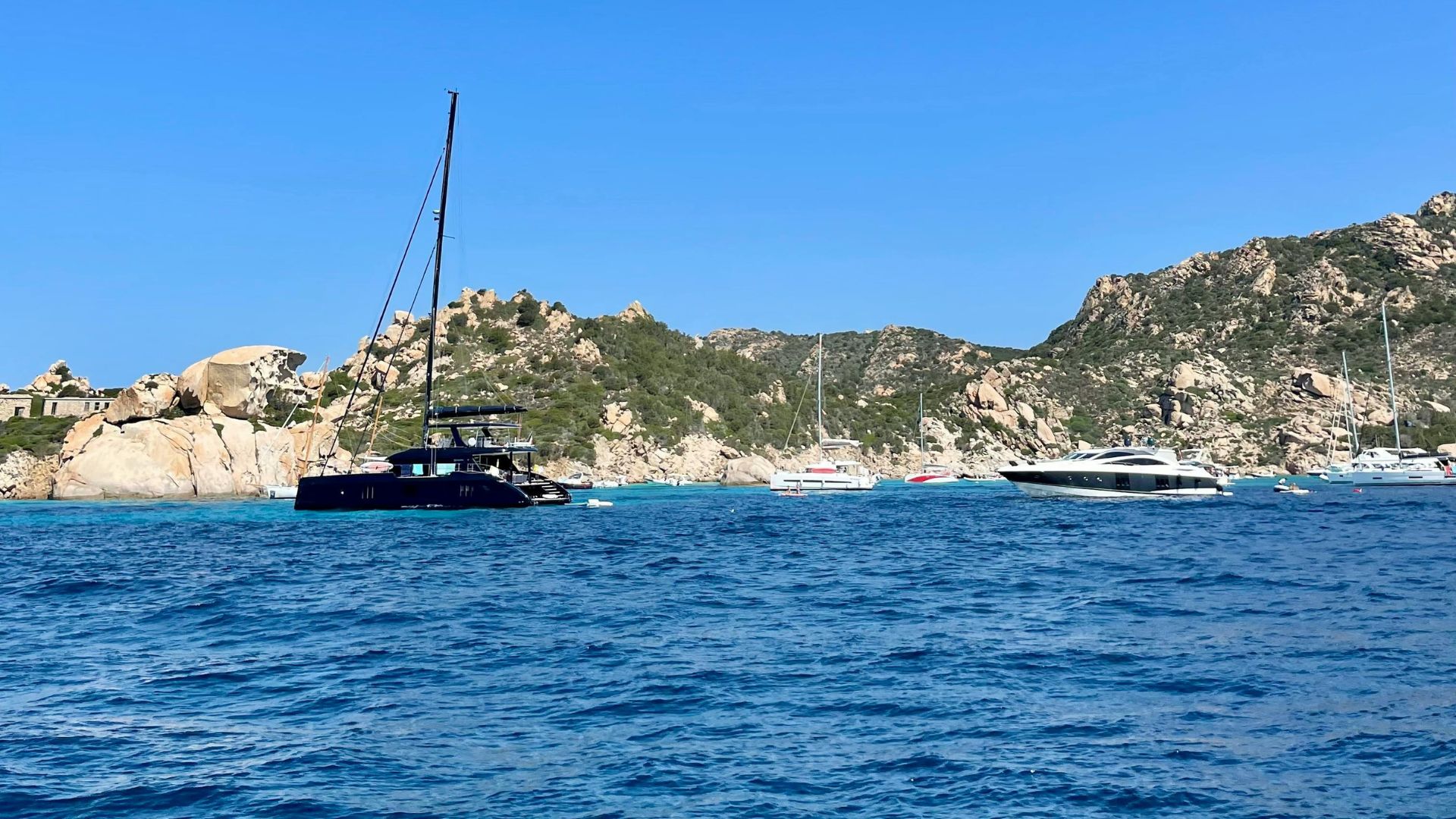 Deep blue skies and waters, greenery, and boats at La Maddalena in Sardinia, Italy.