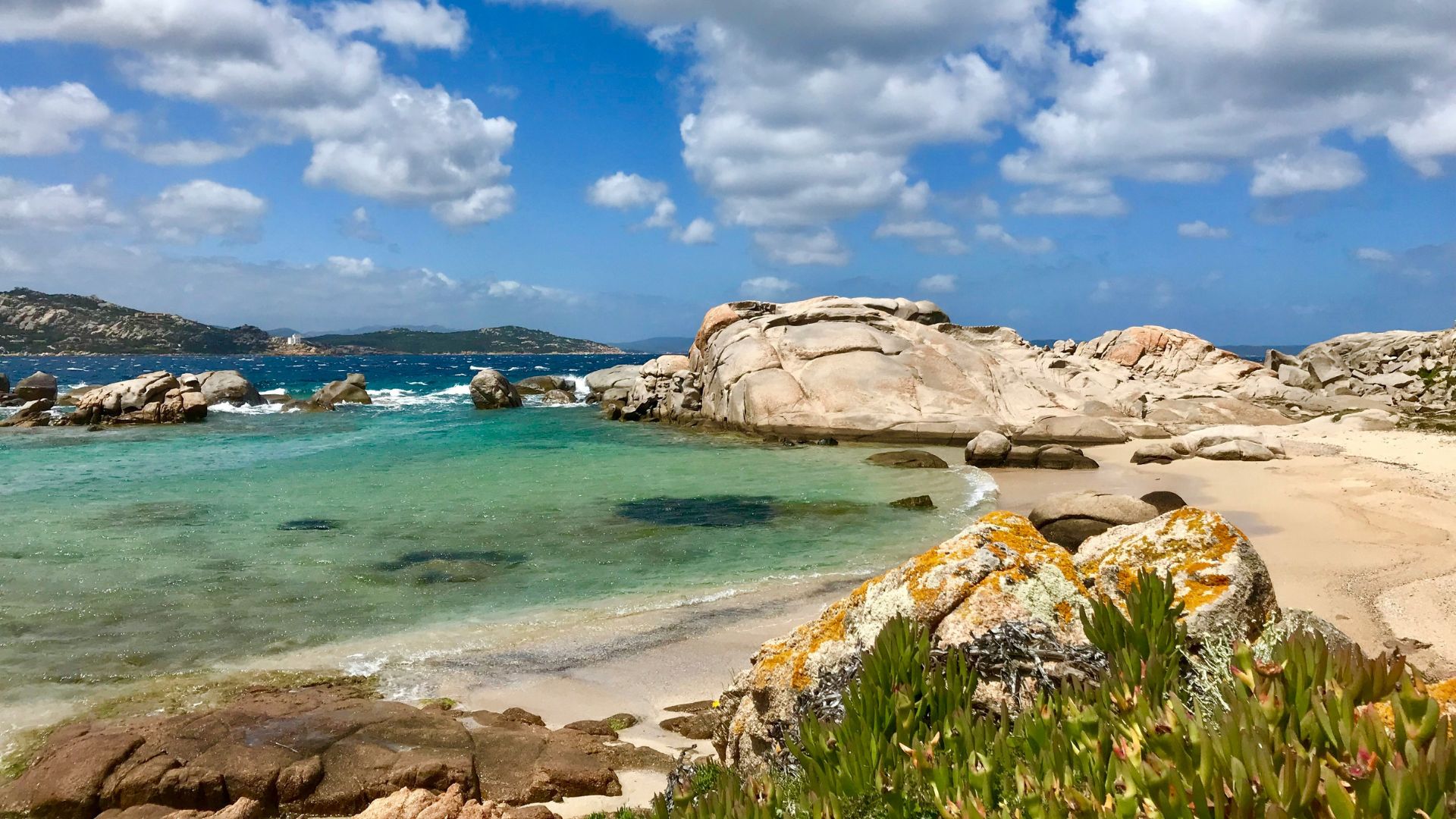 Scenic view of clear waters rocky cliffs and white sand beach.