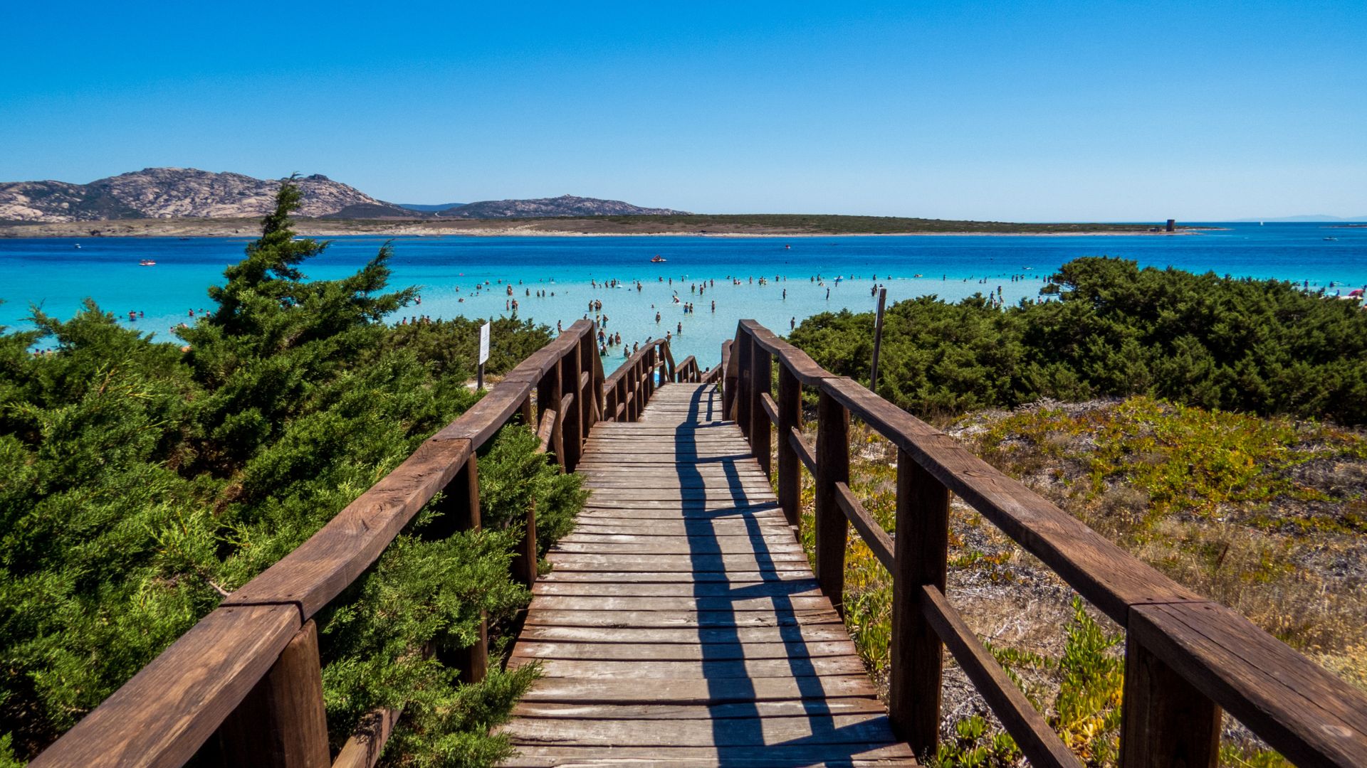 Scenic view of wood  walkways to turquoise blue waters of La Pelosa, Sardinia, Italy.