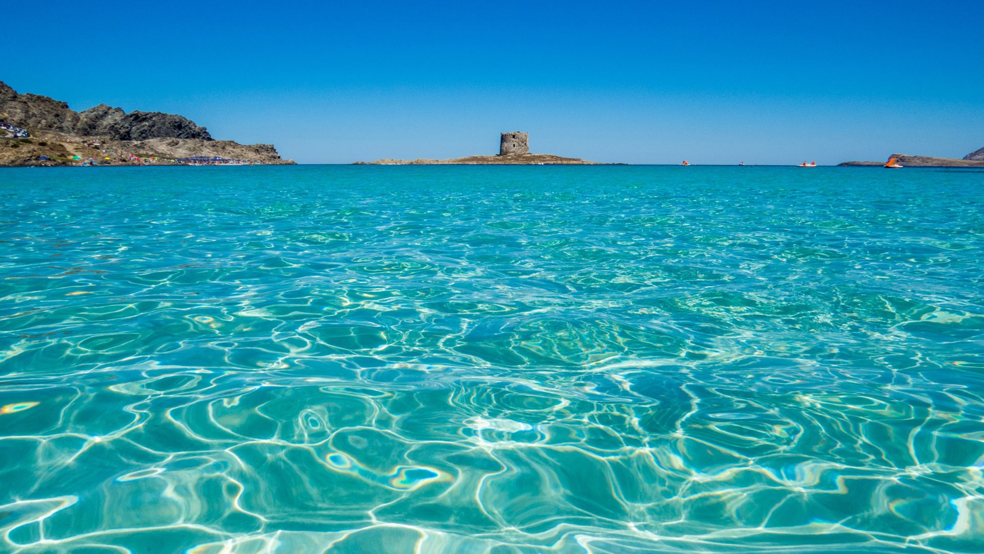 Crystal-clear turquoise water at La Pelosa Beach, Sardinia.
