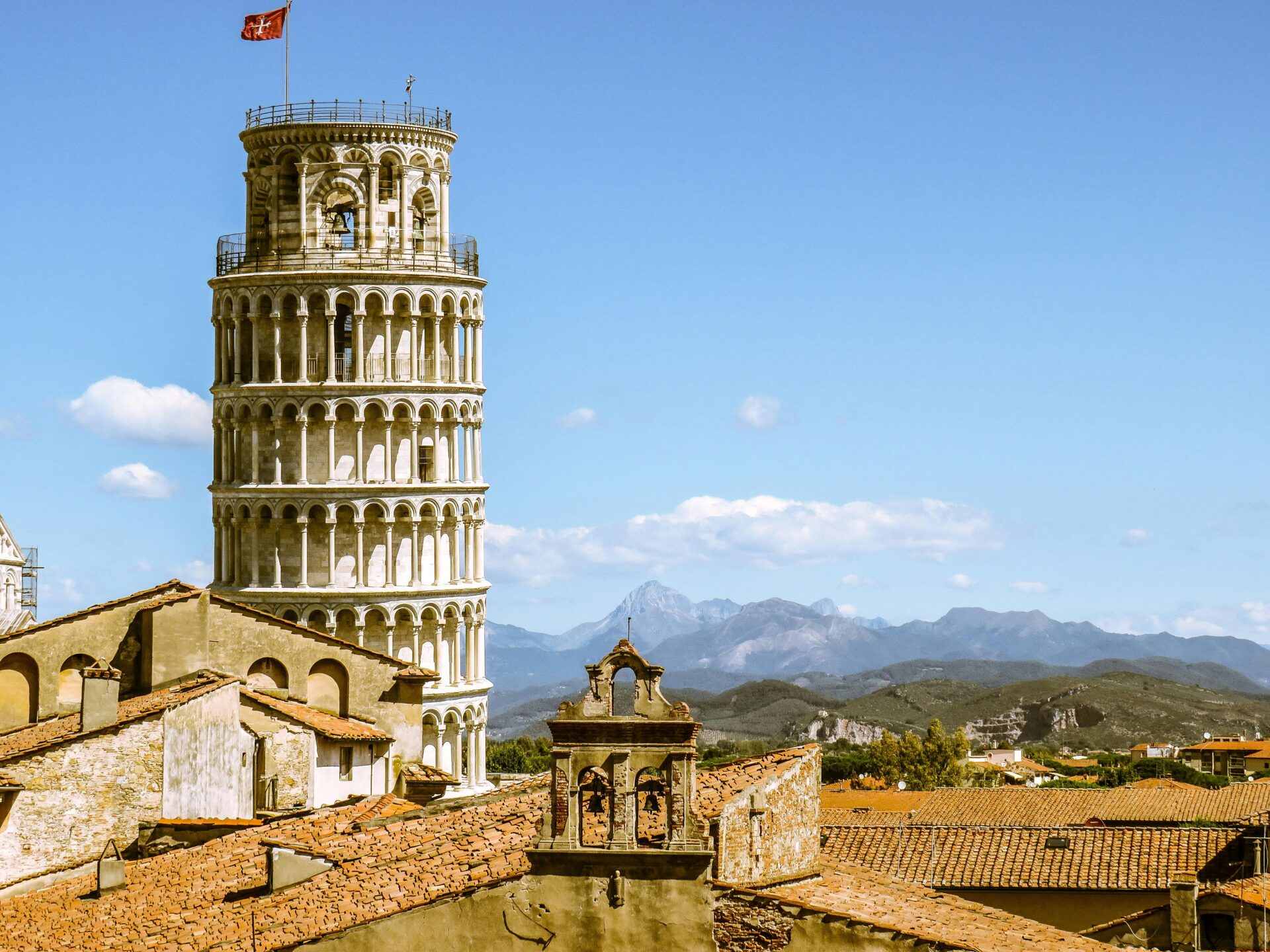 Leaning Tower with Town Roofs and Mountain Landscape
