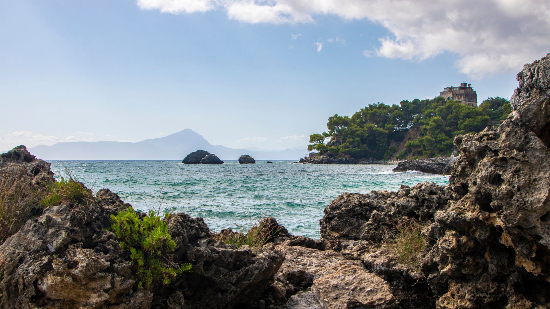 Image shows a rocky cliff and blue water in Marate, Basilicata, Italy.