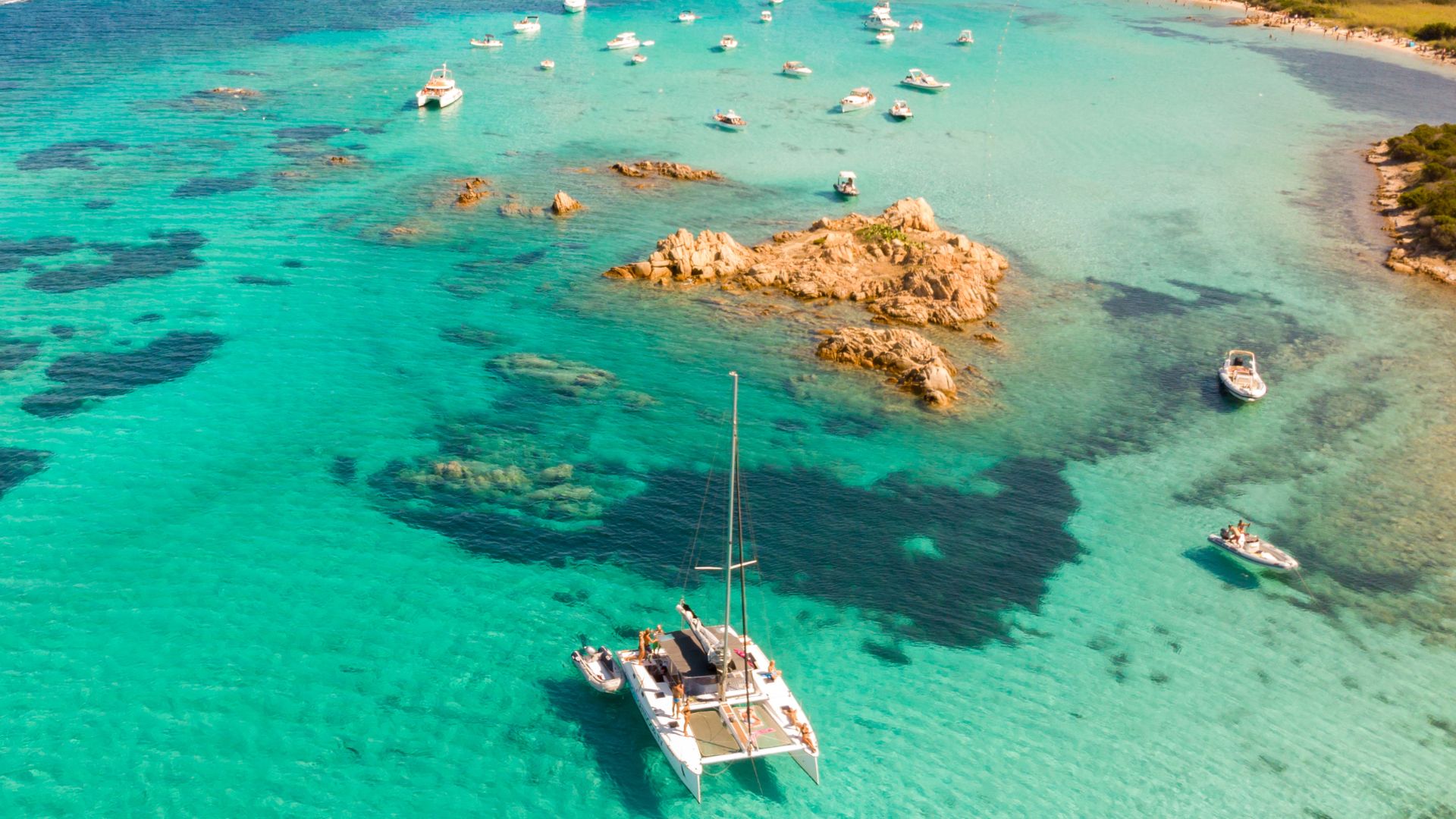 Aerial view of the Maddalena archipelago, featuring turquoise waters, rocky islands, and boats.