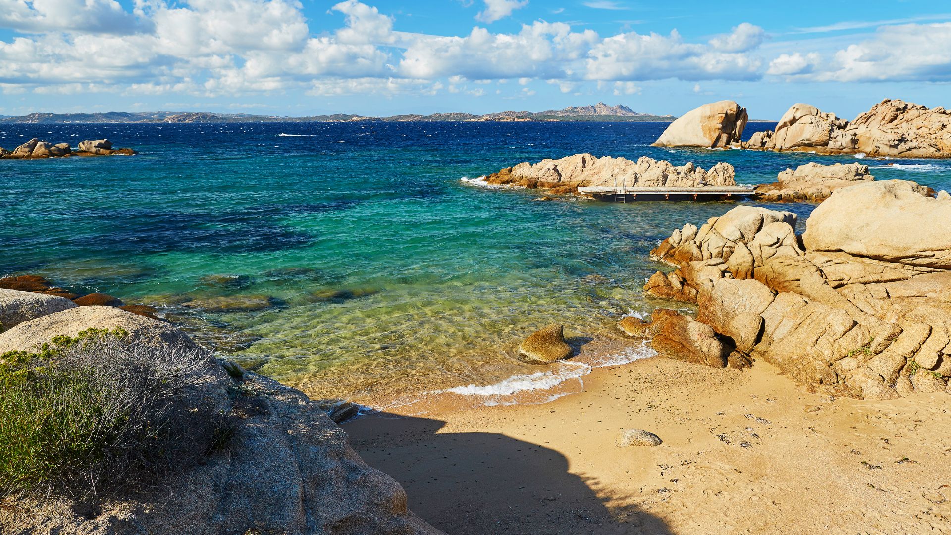 Scenic view of a beach with clear turquoise water and rocky formations in the Maddalena archipelago, Sardinia, Italy.