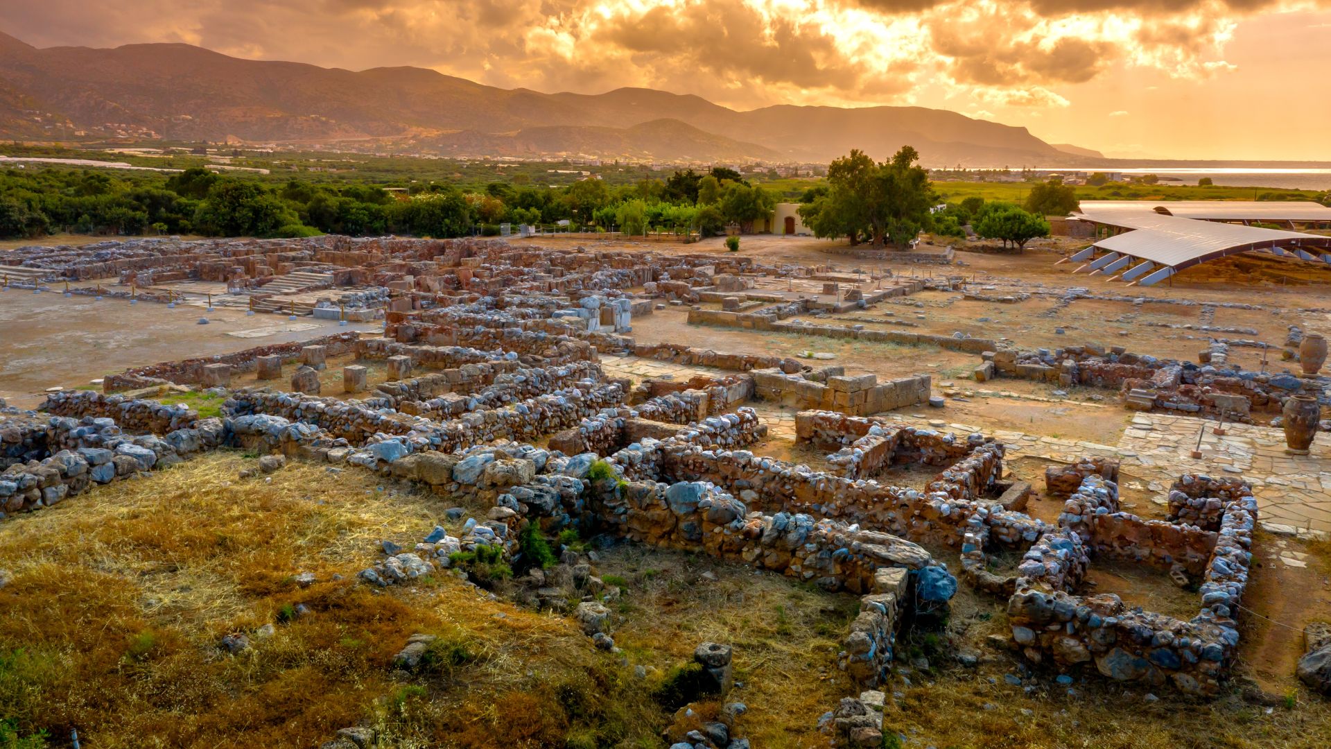 Aerial view of the ruins of the Malia Minoan Palace in Crete, bathed in the warm light of sunrise.