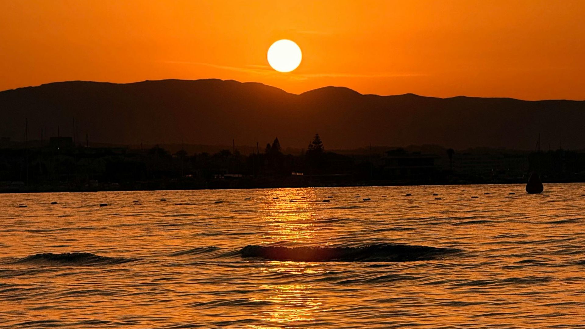 Sunset over a body of water with mountains in the background.