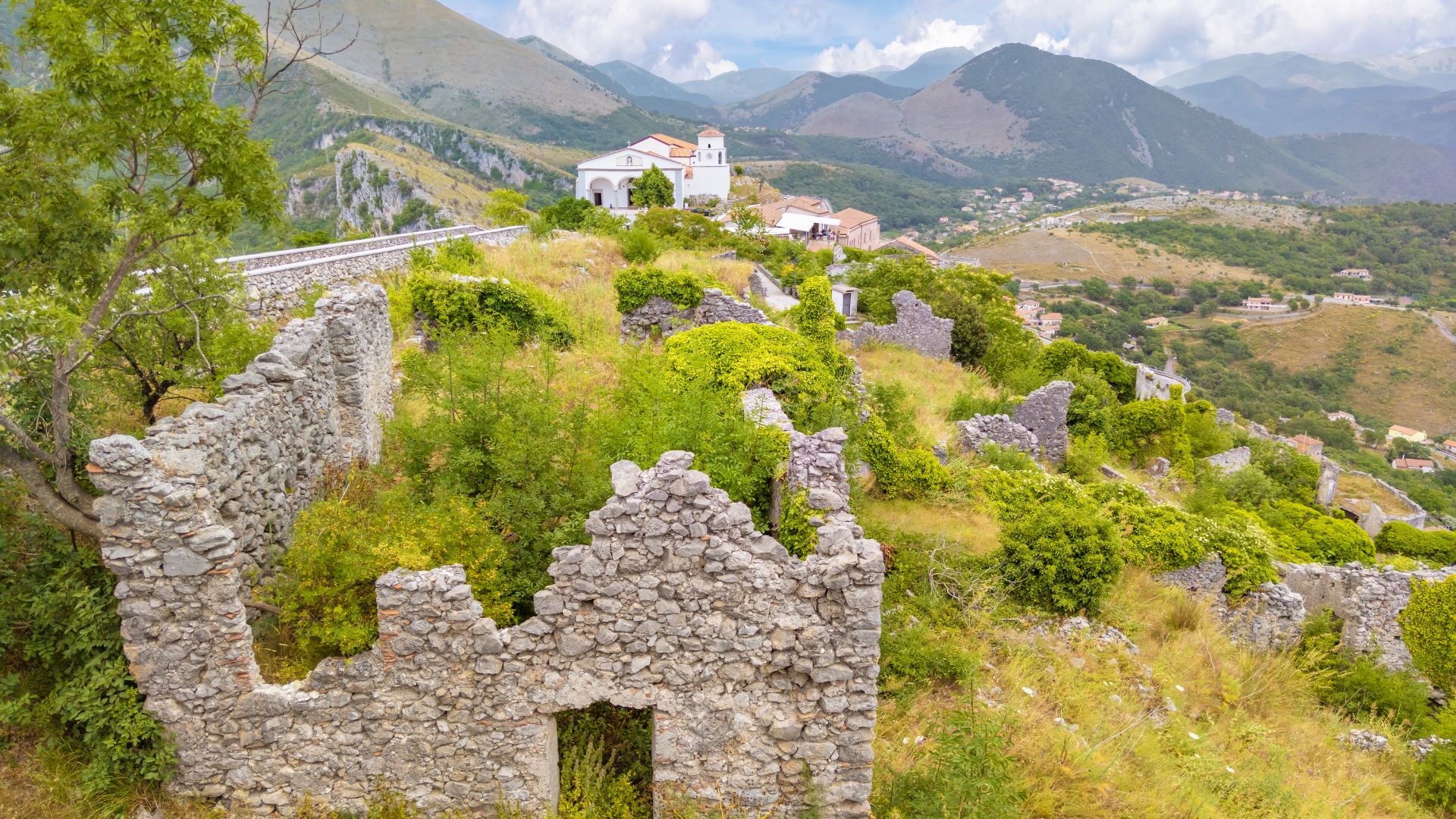 The image shows the ruins of Rivello, an ancient village, and the Basilica di San Biagio, also known as Cristo Redentore, located in the town of Rivello in the province of Potenza, Italy. 