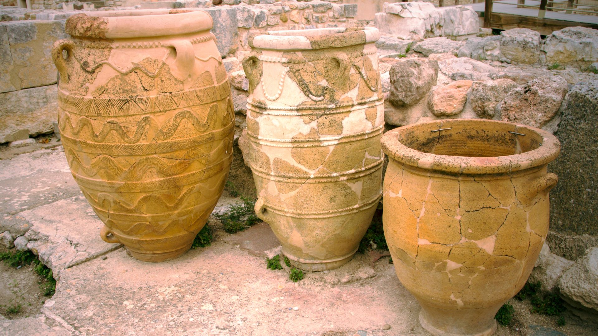Three large, ancient Minoan earthenware storage jars with painted designs.