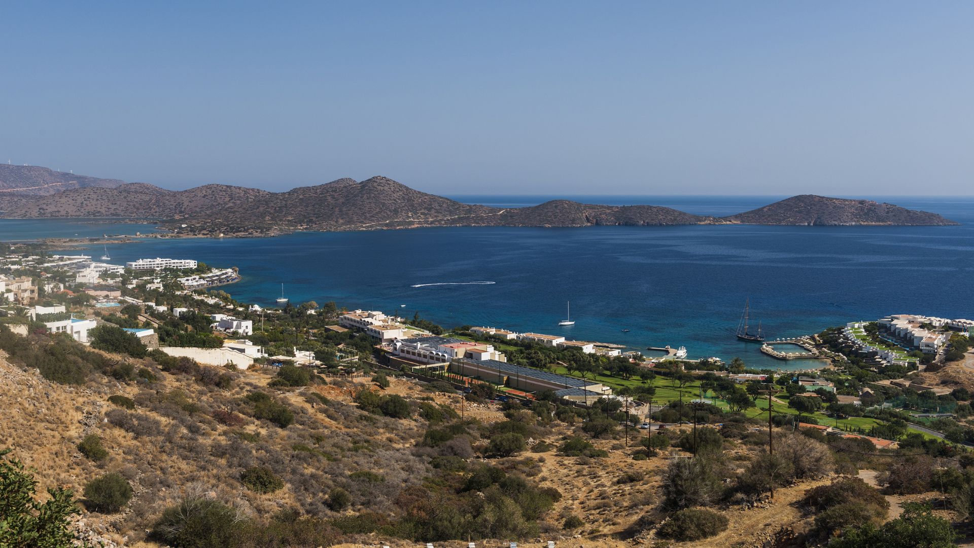 Panoramic view of Mirabello Bay in Crete, Greece, featuring the coastline, mountains, and clear blue waters.