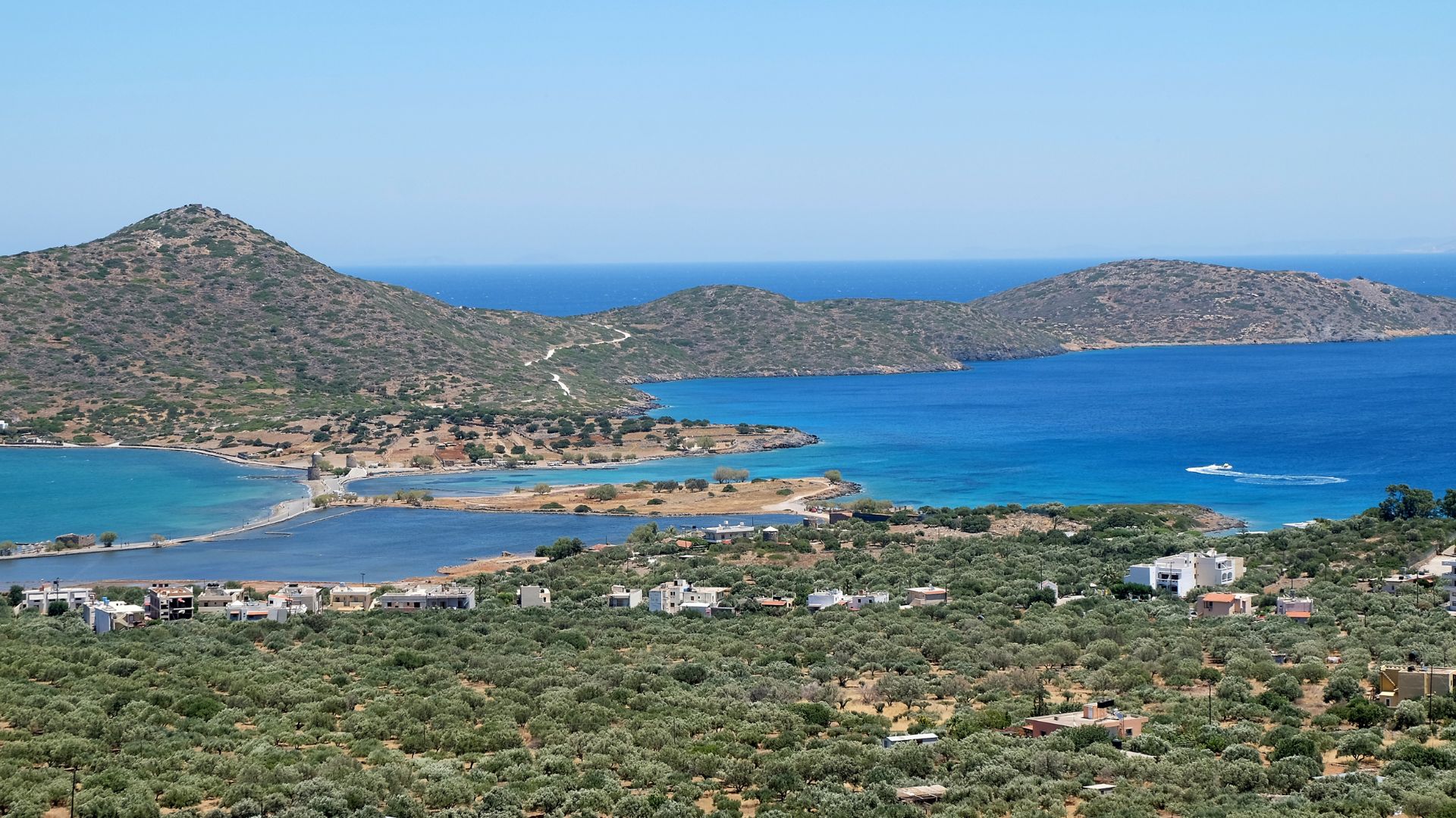 Panoramic view of Mirabello Bay in Crete, Greece, featuring the coastline, mountains, and clear blue waters.