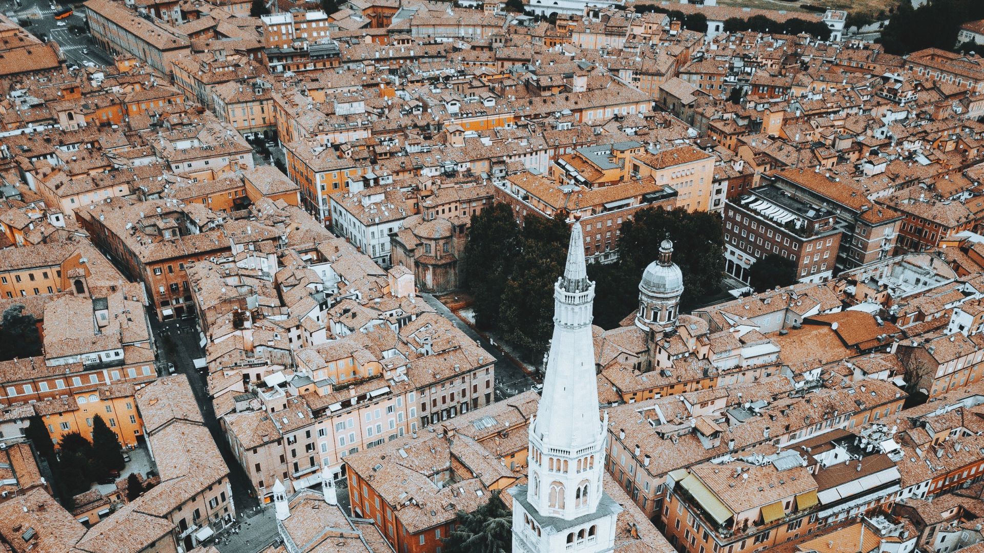 Aerial view of the Ghirlandina tower in Modena, surrounded by the city's rooftops.
