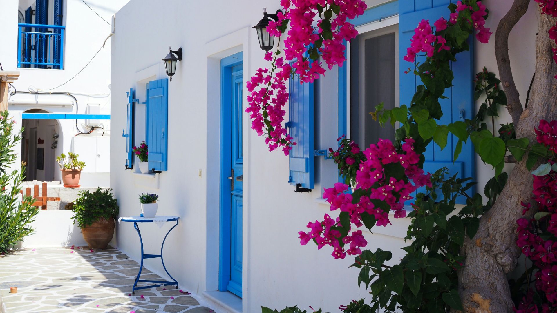 Whitewashed building with blue accents and pink bougainvillea in Mykonos, Greece.