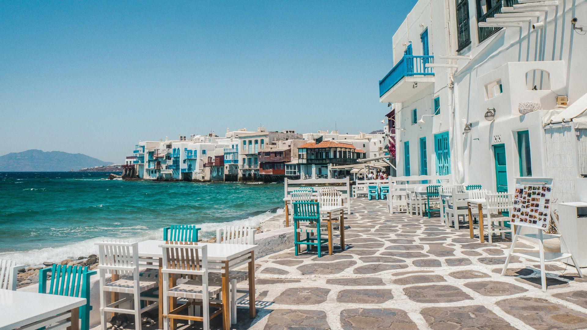 Seaside view of Mykonos' Little Venice with colorful buildings and waterfront tables.