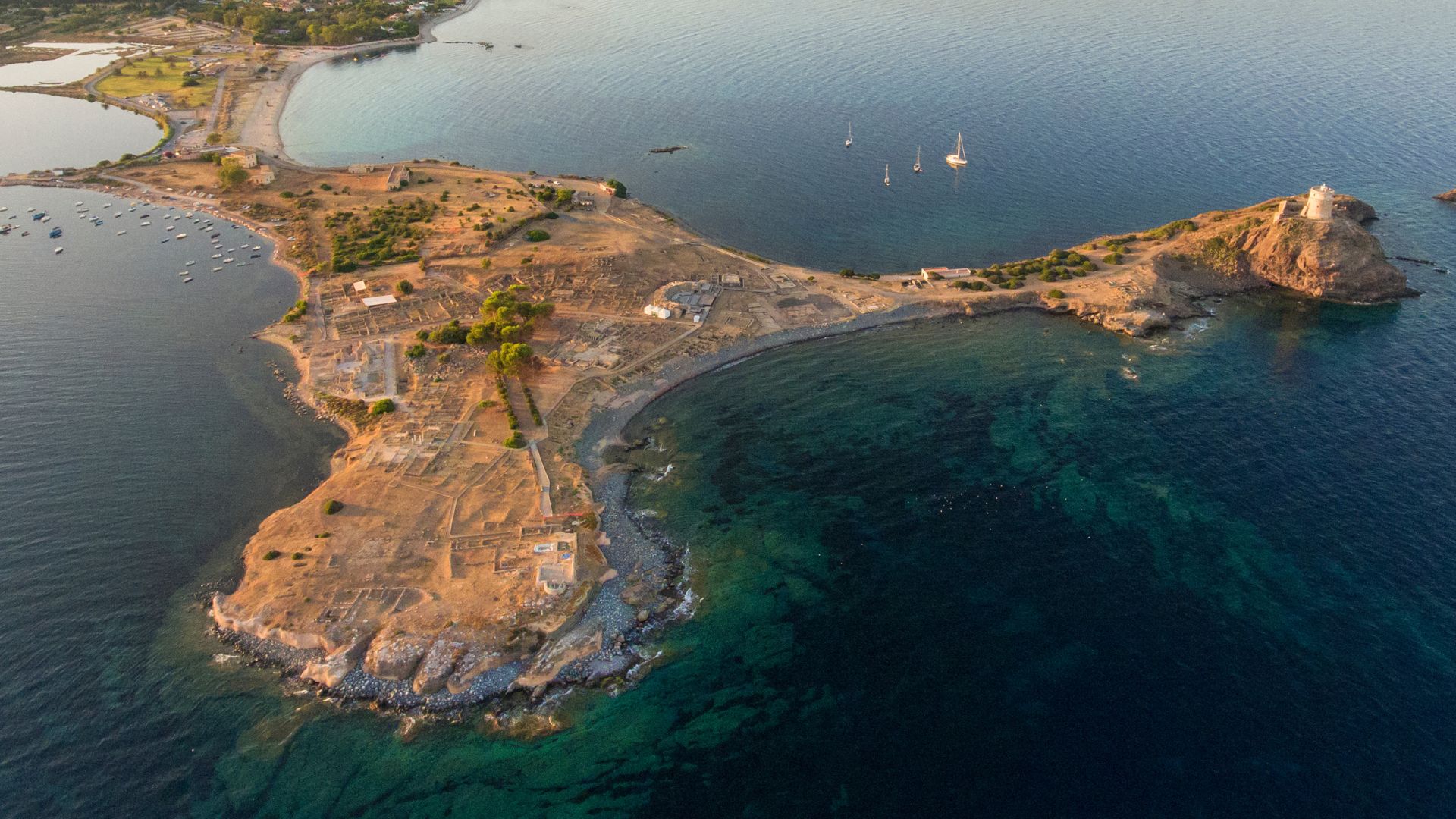 Aerial view of the ancient city of Nora, situated on a peninsula in Sardinia, showcasing its ruins and coastal landscape.