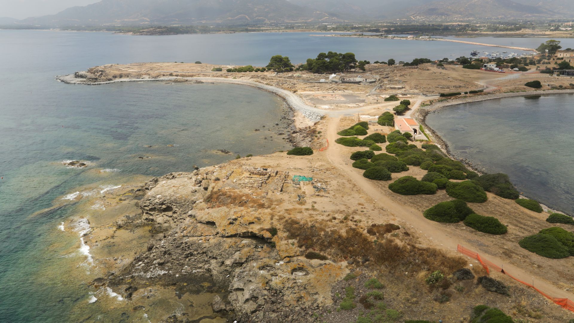 Aerial view of the Nora peninsula in Sardinia, showcasing the ancient ruins, coastline, and lagoon.